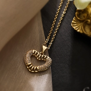 Chic gold-plated heart pendant necklace with shimmering zircon stones on textured fabric