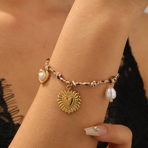 Bohemian woven rope bracelet with heart charms and baroque pearl on a woman's wrist
