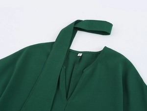 Dettaglio dello scollo dell'abito verde scuro con etichetta taglia S e tessuto liscio
