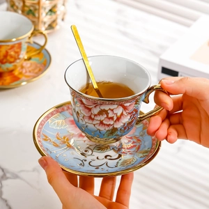 European floral ceramic coffee cup and saucer set with gold spoon on marble surface