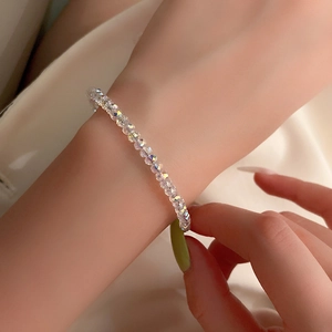 Dettaglio di braccialetti in cristallo con sfaccettature iridescenti sul polso