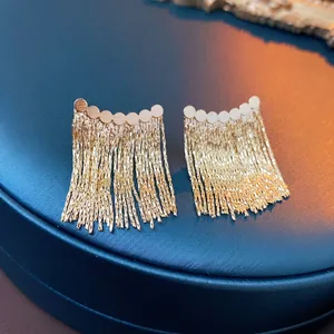 Elegant gold metal chain tassel stud earrings with round discs on a navy blue tray
