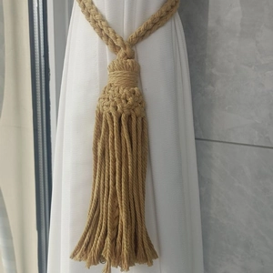 Detail of bohemian cotton rope curtain tieback with handcrafted weave and long tassels