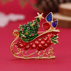 Christmas sleigh brooch with green enamel tree and colorful decorations on red background