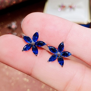 Detailed shot of dark blue marquise-cut zircon flower stud earrings held by hand