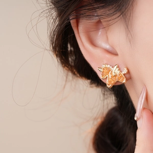 Close-up of golden unicorn stud earring with amber resin and sparkling rhinestones
