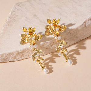 Detail of gold floral earrings with pearls on a natural stone surface
