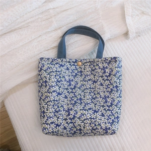 Close-up of blue floral lunch bag with white flower pattern and golden metal snap button