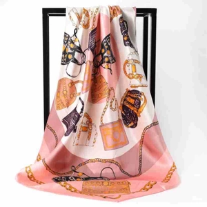 Detail of silk scarf showing pink and white fabric with gold chain and bag patterns