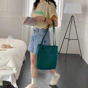 Detail view of a forest green cotton canvas tote bag carried over the shoulder for daily use