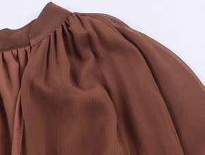 Macro shot of brown chiffon fabric detailing pleated ruffles and sheer texture on dress
