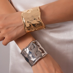 Détail de larges bracelets texturés en or et argent portés par un mannequin