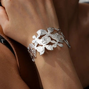 Detail of silver hollow flower cuff bracelet showing intricate floral metalwork on wrist