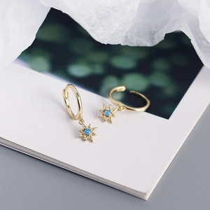 Detailed macro view of S925 silver gold-plated hoop earrings with blue opal star pendants