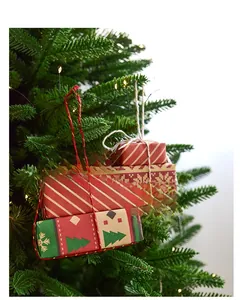 Close-up of stacked red and green mini Christmas gift box ornaments on a tree branch