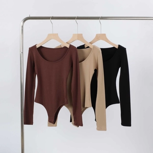 Three long sleeve ribbed bodysuits in brown, beige and black hanging on a rack