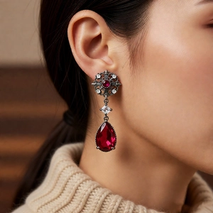 Close-up of vintage flower earrings with red teardrop gemstones worn by a model