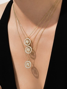 Détail de colliers dorés à trois couches avec trèfle en zircon portés par un mannequin