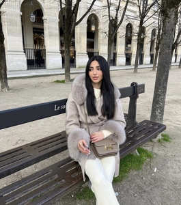 Détail du manteau en laine avec col en fourrure et sac à main de luxe avec boucle en H