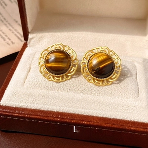 Gros plan détaillé de boucles d'oreilles vintage en or avec pierre œil de tigre ronde
