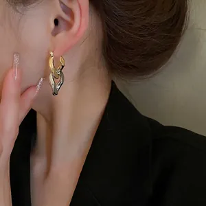 Boucles d'oreilles minimalistes à maillons entrelacés or et argent sur un mannequin
