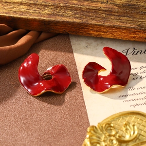 Irregular red enamel earrings with gold trim on vintage aesthetic background for festive season