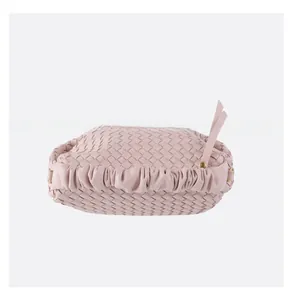 Detail of soft pink woven leather bag with pleated edges and gold hardware details