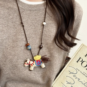 Close-up of handmade horse embroidery pendant with wooden beads on adjustable cord