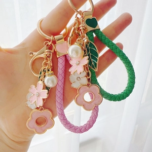 Floral enamel keychains with rhinestones and woven straps in pink and green colors