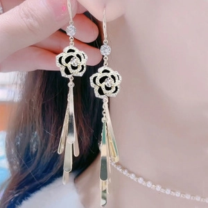 Detail of pink floral earrings with long gold tassels and sparkling rhinestones