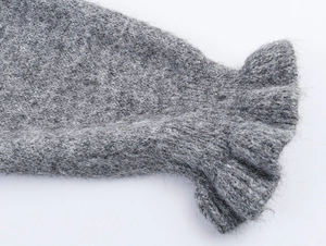 Gros plan détaillé du tricot en mohair gris montrant les poignets à volants et la laine