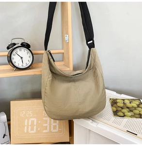 Khaki crescent moon nylon messenger bag hanging in a cozy lifestyle setting