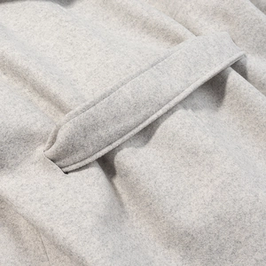 Vue macro d'une poche sur un manteau en laine grise montrant la couture et la texture du tissu