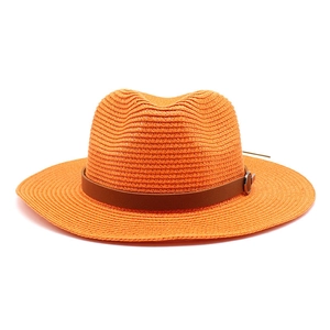 Detail of orange woven straw hat showing the brown leather band and metal buckle