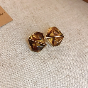 Detail view of amber resin geometric earrings with gold plated edges on linen background