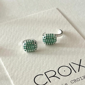 Macro shot of 925 sterling silver hoop earrings with pave set emerald green zircons