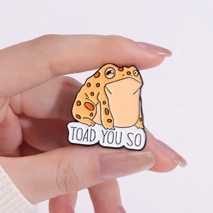 Enamel toad brooch with TOAD YOU SO pun held in hand showing miniature size
