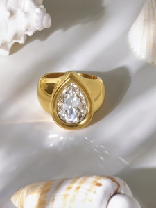 Détail d'un zircon taille poire serti dans une large bague en acier doré à l'or 18 carats
