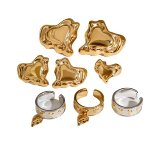 Golden heart stud earrings and stainless steel rings set displayed on white background