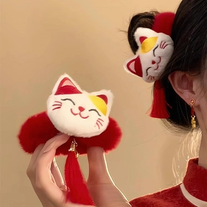 Detail of plush Maneki Neko hair scrunchie with red tassels and Chinese style charm