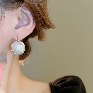 Vue détaillée des boucles d'oreilles perles double face avec fermoir doré sur l'oreille