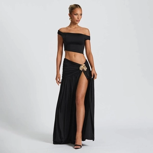 Detail of black two-piece set featuring a cropped top and high-slit skirt with gold buckle