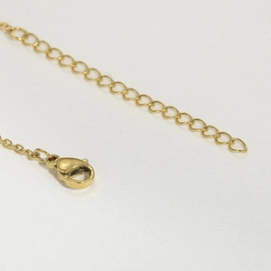 Detailed macro view of the golden necklace lobster clasp and adjustable extension chain