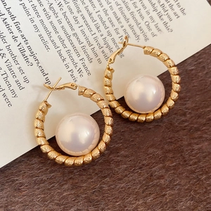 Detailed view of elegant gold-plated twisted hoops with central large round white pearls
