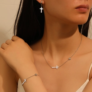 Femme élégante portant collier et bracelet en acier argenté avec croix et cristaux clairs