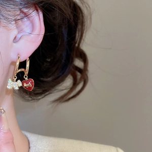 Detailed macro view of gold-plated puppy and red enamel heart charms on small hoop earrings