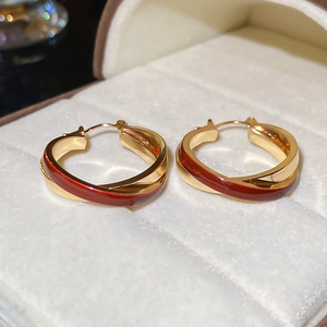 Close-up of vintage red enamel criss-cross hoop earrings on a white velvet jewelry box