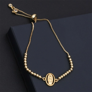 Detail of adjustable gold Virgin Mary charm bracelet with snowflake zircon eye on a display box