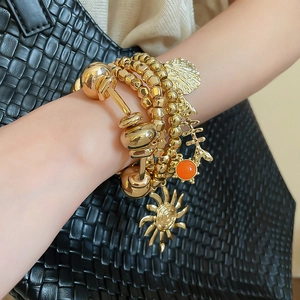 Detail of layered gold beaded bracelets with sun and shell charms on model wrist
