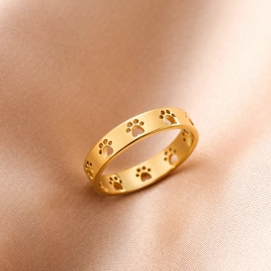 Polished gold cutout cat paw print stainless steel ring on silk background